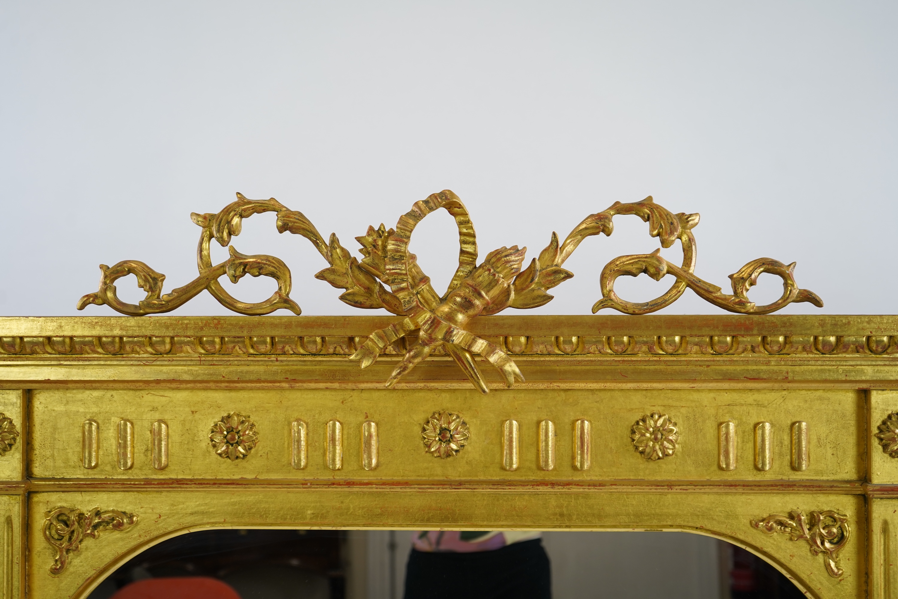 A Victorian style giltwood and composition triple plate overmantel mirror, with foliage scroll torch pediment over a flower head frieze and fluted pillars, 222cm wide,152cm high
